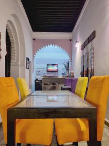 a dining room with a table and yellow chairs at Riad7 in Azemmour