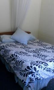 a bed with a blue and white comforter and a pillow at Tekao Lodge in Te Kao