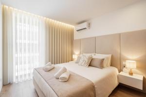 a bedroom with a large bed with two towels on it at Seaside Beach Condo by Minho's Guest in Apúlia
