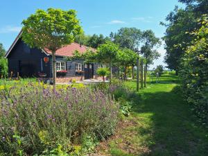 a garden with purple flowers in front of a house at B&B De Oase in Bergambacht +17 photos