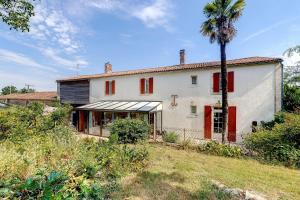 an old house with red shutters and a palm tree at Chambres D'hôtes Le Peux in Saint-Pierre-le-Vieux