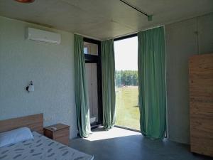 a bedroom with a large window with green curtains at IO House in Urekis Sadguri