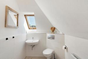 a white bathroom with a toilet and a sink at Ferienwohnung "Am Waldrand" in Bottrop +10 photos