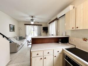 a kitchen with wooden cabinets and a living room at STAY Sea Gem Townhouse in Meneou