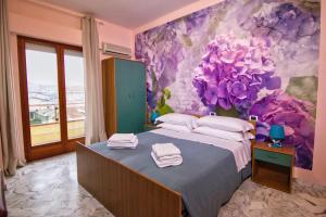 a bedroom with a large bed with purple flowers on the wall at Hotel Roma in Pineto