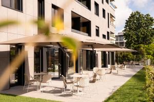 an outdoor patio with tables and chairs and umbrellas at THE FLAG Lugano - Self Check-in in Massagno