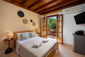 a bedroom with a bed and a television and a patio at Pinotsi Rooms Village Symi in Symi