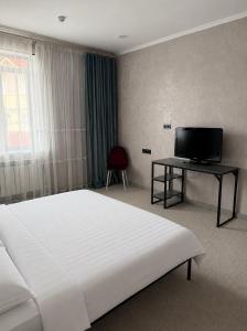 a bedroom with a white bed and a television at AiTumar boutique hotel in Almaty +9 photos
