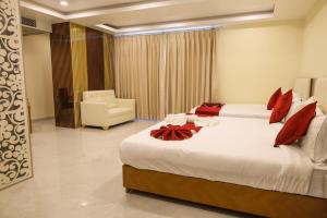 a hotel room with two beds and a chair at Briddhishree Palace in Guwahati