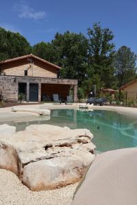 a swimming pool with a rock in front of a house at Chalet tous confort avec piscine lagon in Vallon-Pont-dʼArc