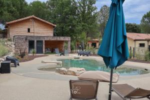 a pool with chairs and an umbrella in a yard at Chalet tous confort avec piscine lagon in Vallon-Pont-dʼArc