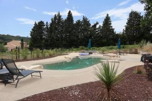 a swimming pool in a yard with chairs and avisor at Chalet tous confort avec piscine lagon in Vallon-Pont-dʼArc +14 photos