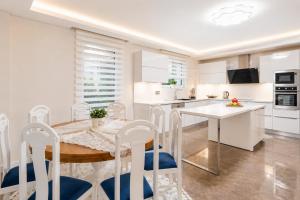 a white kitchen with a wooden table and chairs at Villa Ozcelik in Dalyan