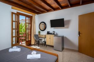 a bedroom with a bed and a desk and a television at Pinotsi Rooms Village Symi in Symi +33 photos