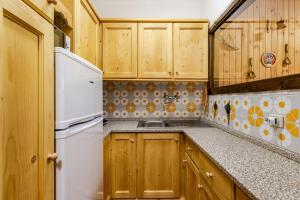 a kitchen with wooden cabinets and a white refrigerator at Eldann Apartment - Tradizione e Relax a Sappada in Sappada