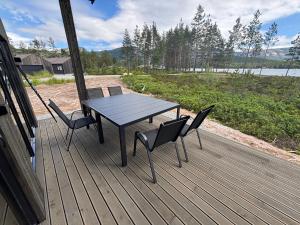 a wooden deck with a table and chairs on it at Nisserstrand Hytte mit WLAN und Sauna direkt am See in Treungen