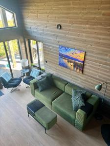 a living room with a green couch and chairs at Nisserstrand Hytte mit WLAN und Sauna direkt am See in Treungen