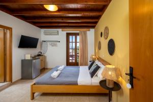 a bedroom with a large bed and a television at Pinotsi Rooms Village Symi in Symi