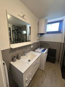 a white bathroom with a sink and a mirror at LA CASETTA di AURORA in Riomagno