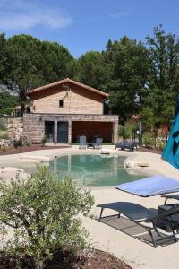 a swimming pool with chairs and a building at Tente chauffée avec piscine lagon in Vallon-Pont-dʼArc
