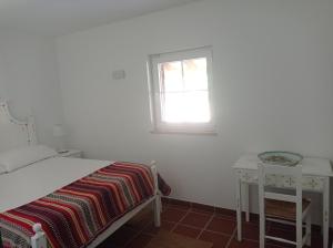 a white bedroom with a bed and a window at Typical Alentejo House in Mora