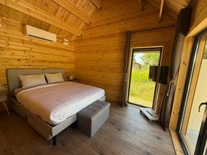 a bedroom with a bed in a log cabin at Chalet en bois indépendant, terrasse et accès piscine in Montret