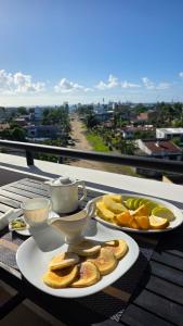 two plates of food on a table with cups and oranges at Miami Suites Tamatave in Toamasina