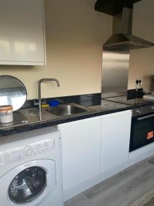 a kitchen with a sink and a washing machine at Keethz Home in Timperley