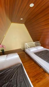 two beds in a room with a wooden ceiling at villa cabin vianda in Kejajar
