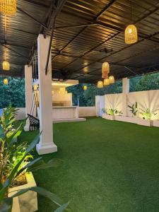 a patio with green grass and pendant lights at The Lamendriea Hotel in Kalagedihena +1 photo