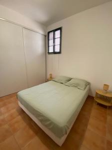 a white bedroom with a bed and a window at APPARTEMENT Malana in Nîmes