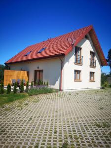 a white house with a red roof at Dom Gościnny Ogrodowa in Wiślinka
