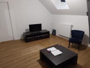 a living room with a tv and a table and a chair at Aux Cormulets in La Baconnière