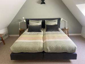 a bedroom with a bed with pillows on it at UNIEK Bommelgaard, guesthouse in het prachtige Rivierenland! in Hurwenen