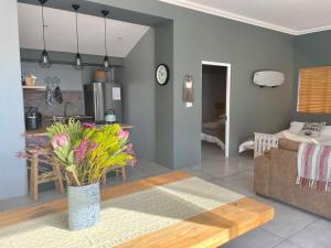 a living room with a couch and a table with flowers at The Kite Cottage in Langebaan