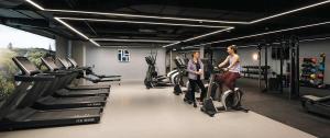two people standing on exercise bikes in a gym at Large Luxurious Studio, Dublin18 in Dublin
