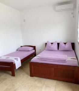 two beds in a room with purple sheets and pillows at Elit Apartmani in Ulcinj