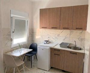 a kitchen with a sink and a table with chairs at Elit Apartmani in Ulcinj