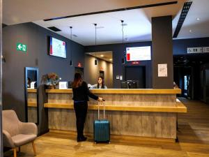 a woman standing at a bar with her luggage at ibis budget Logroño Centro in Logroño