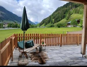 a patio with an umbrella and a chair and a table at Boutique Appartements Kumming inkl Nationalparkcard in Rauris