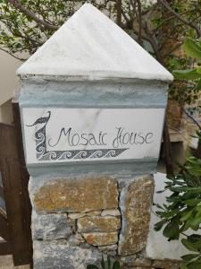 a stone house with a sign that reads mosaic house at Mosaic house by the sea in Kini