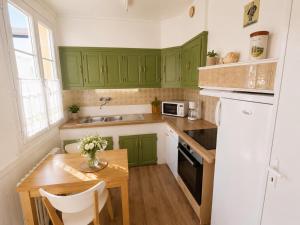 a kitchen with green cabinets and a wooden table at Aux Roses in Saint-Honoré-les-Bains