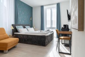a bedroom with a large bed and a chair at Villa Vaicun - Boutique Rooms in Lörrach