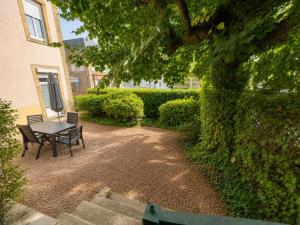 a table and a bench next to a hedge at Aux Roses in Saint-Honoré-les-Bains