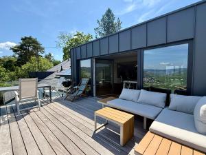 a patio with a couch and a table on a deck at Klimatisiertes Moselloft in Leiwen