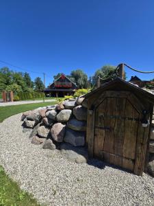 a small wooden shed with a rock wall at Apartament-SŁOVIAŃSKI ZAKĄTEK in Nowakowo