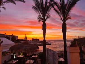 a sunset over the ocean with palm trees at Finalmente in vacanza in Xitta