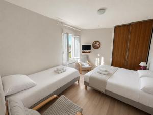 a hotel room with two beds and a chair at Aux Coquelicots in Saint-Honoré-les-Bains