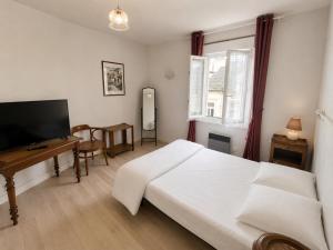 a bedroom with a bed and a desk and a television at Aux Coquelicots in Saint-Honoré-les-Bains