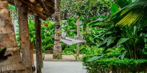 a hammock hanging from a tree in a garden at Tamu Tamu Boutique Hotel in Pwani Mchangani